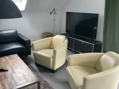 Sitzcouch mit Sesseln und Couchtisch im Wohnzimmer mit Flachbildfernseher