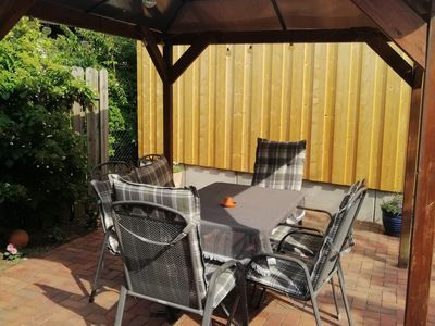 Sonnige, teils überdachte Terrasse mit Tisch und Stühlen