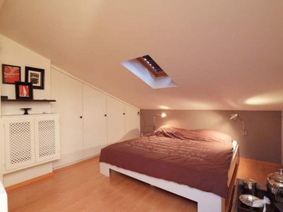 Elternschlafzimmer im Obergeschoss mit Dachschrägen und elegant integriertem offenem Badezimmer.