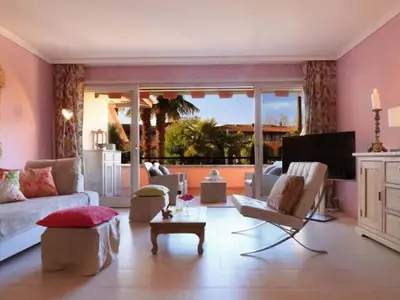 Blick auf das Wohnzimmer und die von Grün umgebene Balkonterrasse. 