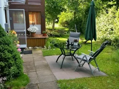 kleine Terrasse mit Sitzgelegenheit und Garten