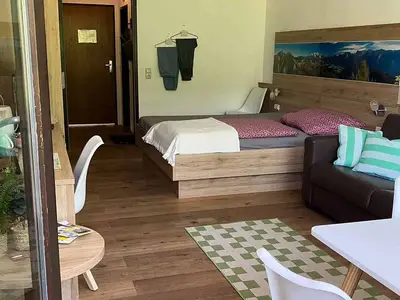 Blick vom Balkon in die Ferienwohnung (Bett, Sofa, Esstisch, Schreitisch & Eingangstüre)