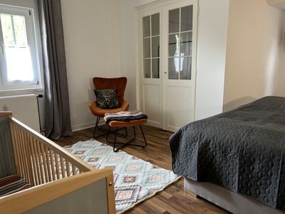Schlafzimmer mit Fernsehgerät, Schreibtisch und Kinderbett