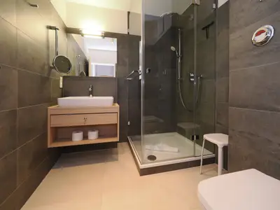 Badezimmer mit Dusche, WC, Waschtisch und Spiegel