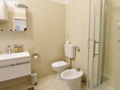 Das komplette Badezimmer mit Dusche, Bidet, Toilette, Spiegel, Waschmaschine und Waschbecken mit Schrank