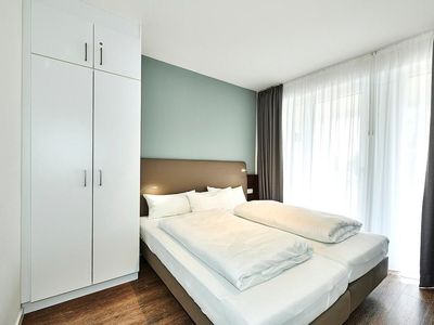 Schlafzimmer mit Doppelbett, Kleiderschrank und Zugang zur Terrasse