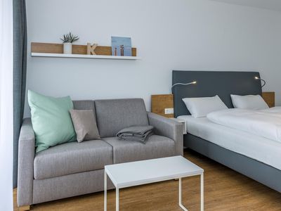 Wohn-Ess-Schlafbereich mit Sofa und Doppelbett