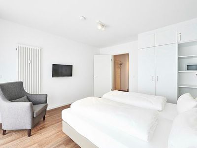 Schlafzimmer mit Doppelbett, Sessel, TV und Kleiderschrank