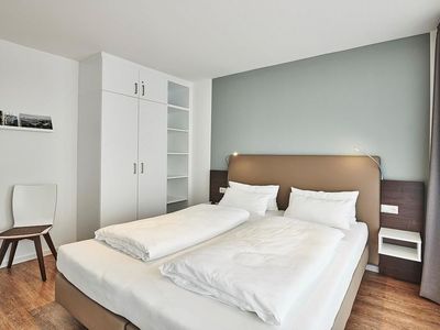 Schlafzimmer mit Doppelbett, Kleiderschrank und Stuhl