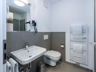 Badezimmer mit Dusche, Waschbecken, WC und Spiegel