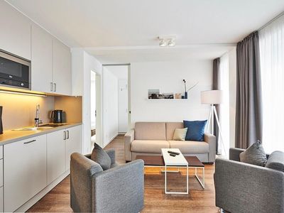 Wohnbereich mit Sofa, Sessel und Küchenzeile