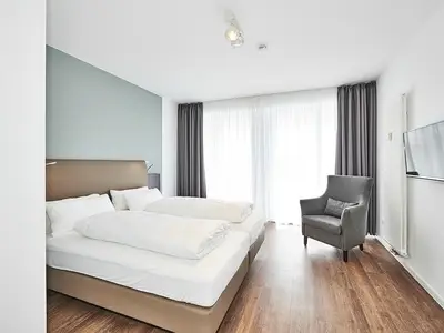 Schlafzimmer mit Doppelbett, Sessel und TV