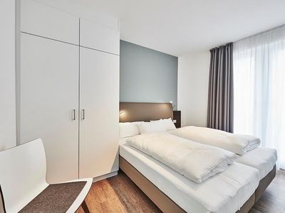 Schlafzimmer mit Doppelbett, Stuhl und Kleiderschrank