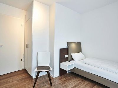 Schlafzimmer mit zwei Einzelbetten, Stuhl und Kleiderschrank