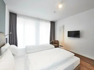 Schlafzimmer mit Doppelbett, Sessel und TV