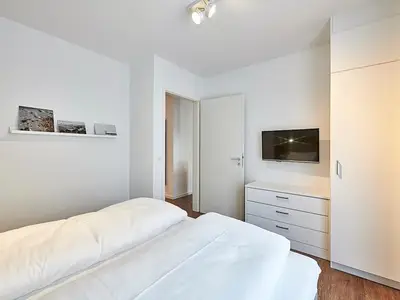 Schlafzimmer mit Doppelbett, Kleiderschrank und TV