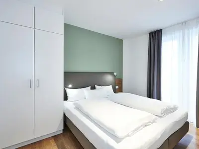 Schlafzimmer mit Doppelbett, Kleiderschrank und Zugang zum Balkon