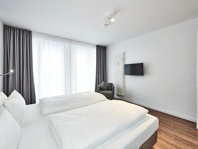 Schlafzimmer mit Doppelbett, Flatscreen-TV und Zugang zum Balkon