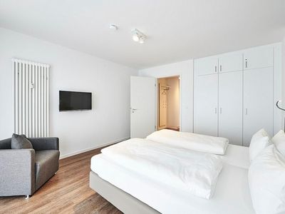 Schlafzimmer mit Doppelbett, Kleiderschrank, Sessel und Flatscreen TV