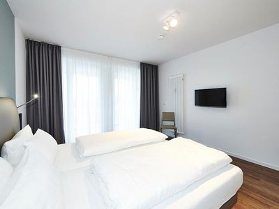 Schlafzimmer mit Doppelbett, Flatscreen TV und Zugang zu Balkon