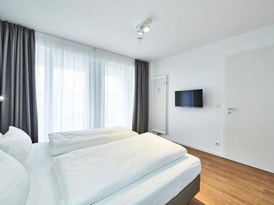 Schlafzimmer mit Doppelbett und Zugang zum Balkon