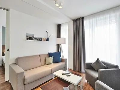 Wohnbereich mit Sofa, Sessel, Couchtisch und Zugang zum Balkon