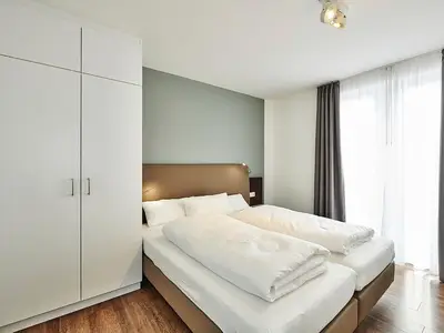 Schlafzimmer mit Doppelbett, Kleiderschrank und Zugang zum Balkon