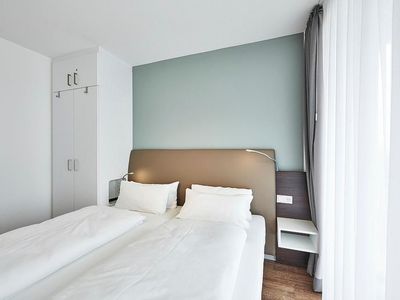 Schlafzimmer mit Doppelbett, Kleiderschrank und Zugang zum Balkon