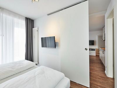 Schlafzimmer mit Doppelbett, Flatscreen-TV und Zugang zum Balkon