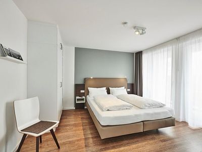 Schlafzimmer mit Doppelbett, Kleiderschrank und Zugang zum Balkon