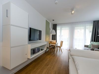 Wohn-Ess-Schlafbereich mit Sofa, Esstisch, und Doppelbett sowie Flatscreen TV