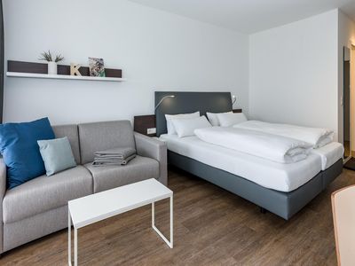 Wohn-Ess-Schlafbereich mit Doppelbett und Sofa