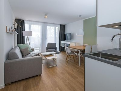 Wohn-Essbereich mit Couch, Esstisch, Sitzgelegenheit und Zugang zum Balkon