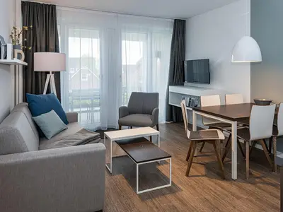 Wohn-Essbereich mit Couch, Esstisch, Sitzgelegenheit und Zugang zum Balkon