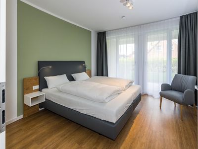 Schlafzimmer mit Doppelbett, Sitzgelegenheit und Zugang zur Terrasse