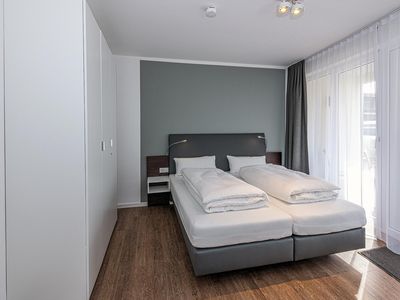 Schlafzimmer mit Doppelbett, Kleiderschrank und Zugang zur Terrasse