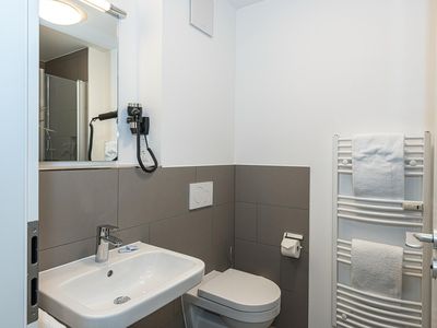 Badezimmer mit Dusche, Waschbecken und Spiegel