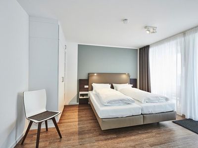 Schlafzimmer mit Doppelbett, Stuhl und Kleiderschrank