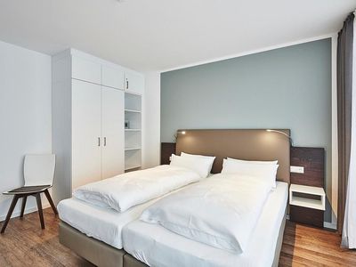 Schlafzimmer mit Doppelbett, Stuhl und Kleiderschrank