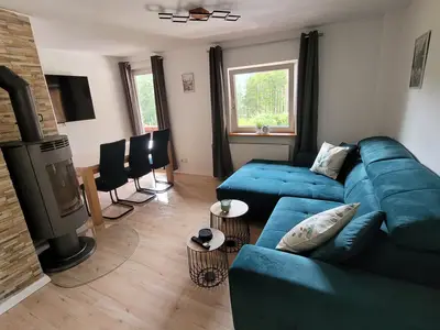 Wohnzimmer mit Holzofen und Schlafsofa sowie Esstisch