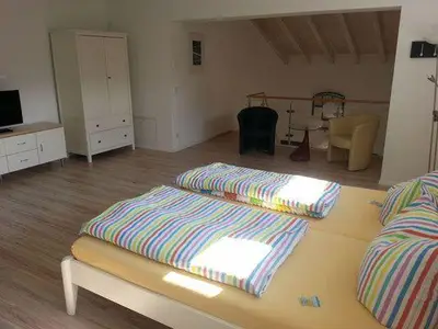 Schlafbereich. Maisonette Ferienwohnung mit Doppelbett (180 cm breit), Fernseher, Schrank und Sitzecke im Obergeschoss