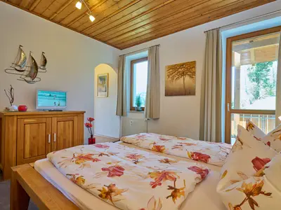 Doppelbett mit Blick auf kleinen Balkon und Durchgang