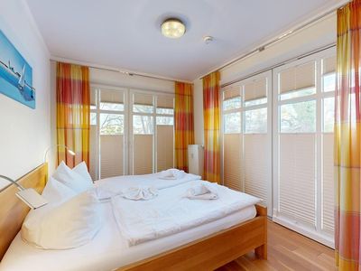 Doppelbett-Schlafzimmer mit großen Fensterfronten und großem Balkon