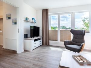 Wohn-/Essbereich mit Sessel, TV und Zugang zur Dachterrasse