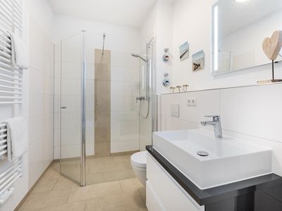 Badezimmer mit Waschtisch, Spiegel und Dusche