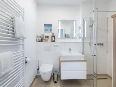 Badezimmer mit Dusche, Waschtisch, Spiegel und WC