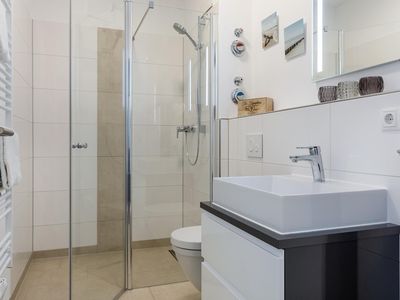 Badezimmer mit Dusche, Waschtisch und Spiegel