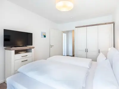 Schlafzimmer mit Doppelbett, Kleiderschrank und TV