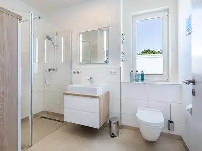 Badezimmer mit Dusche, Waschtisch, Spiegel und WC