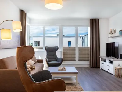 Wohn-/Essbereich mit Doppelschlafcouch, Couchtisch, TV und Zugang zur Dachterrasse